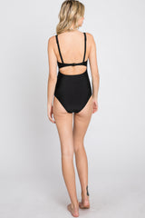 woman wearing a black one-piece swimsuit with a low back and adjustable straps, viewed from the back