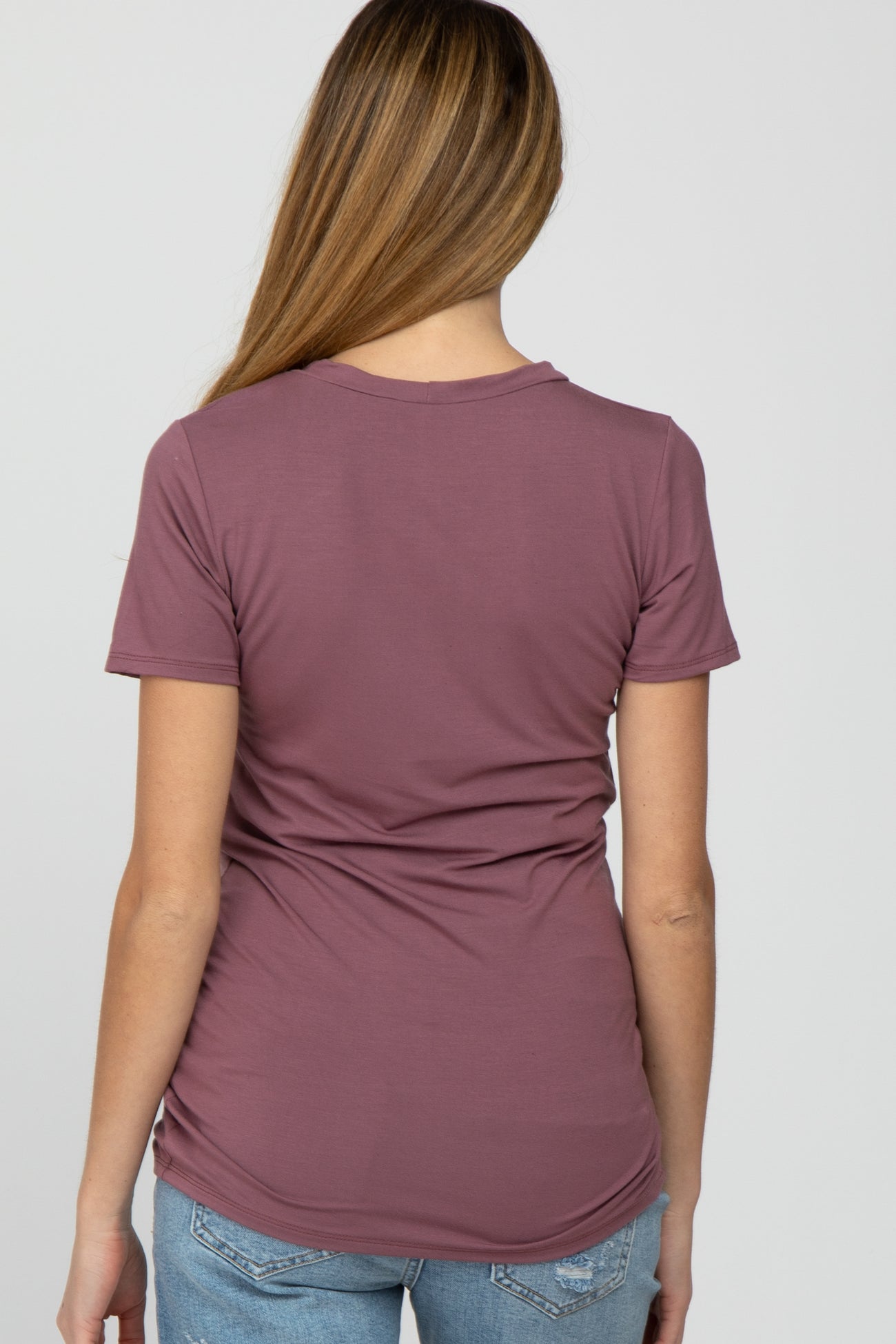 woman wearing a mauve short sleeve maternity top with a fitted style, showing the back view