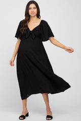 pregnant woman wearing a black short sleeve maternity midi dress with a front tie detail