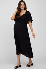 woman wearing a black maternity dress with a tie detail and flutter sleeves, highlighting her baby bump