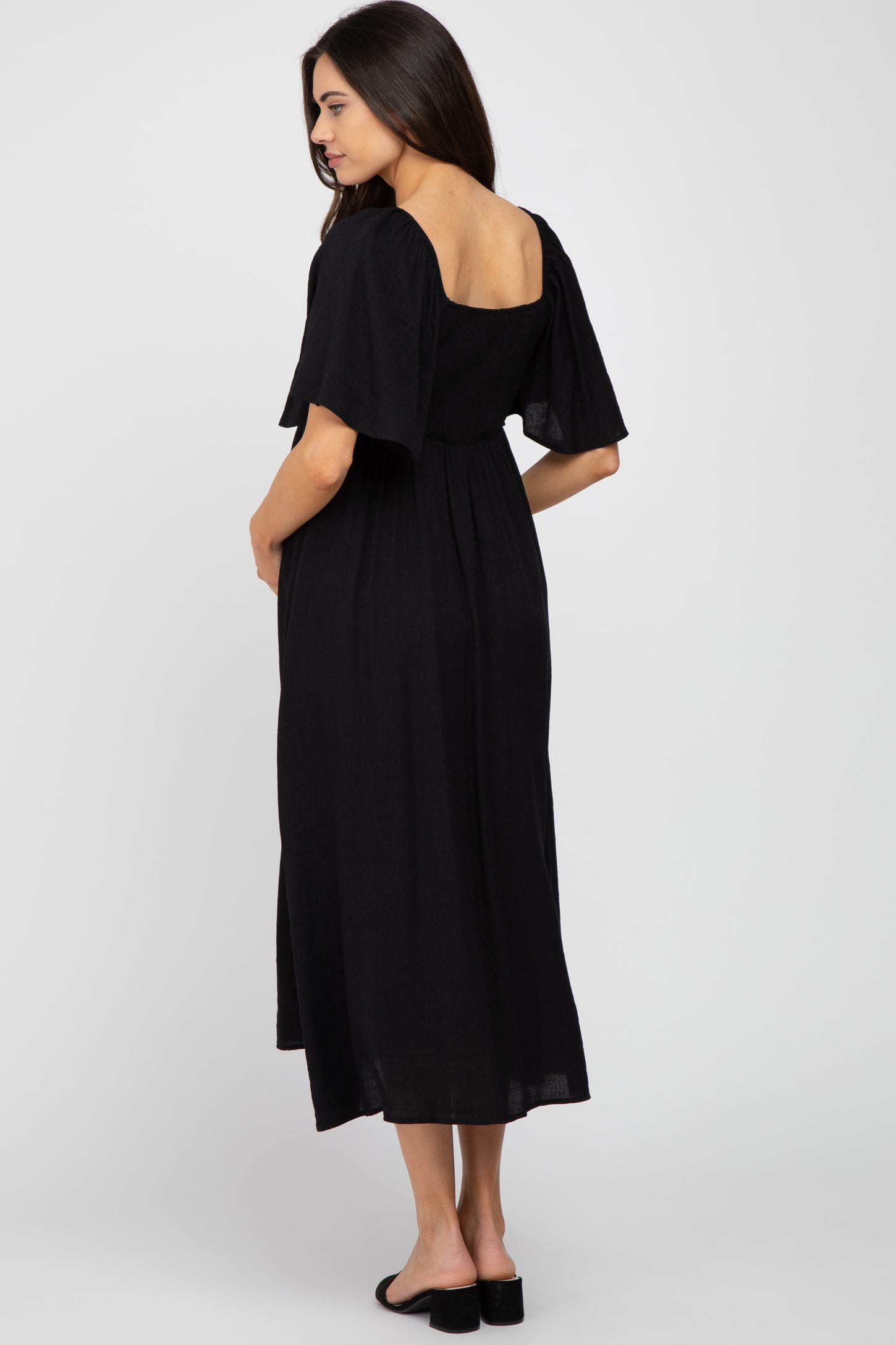 woman wearing a black maternity maxi dress with short flutter sleeves and a cinched waist, viewed from the back