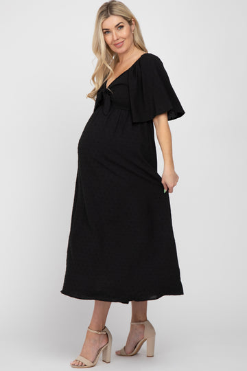 woman wearing a black maternity maxi dress with flutter sleeves and a fitted waist, showcasing her baby bump