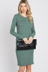 woman wearing a green ribbed knit long sleeve dress and holding a black clutch bag