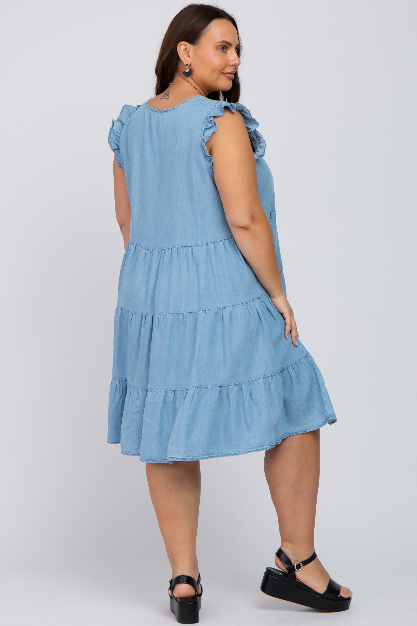 woman wearing a light blue tiered denim dress with ruffle sleeves in plus size