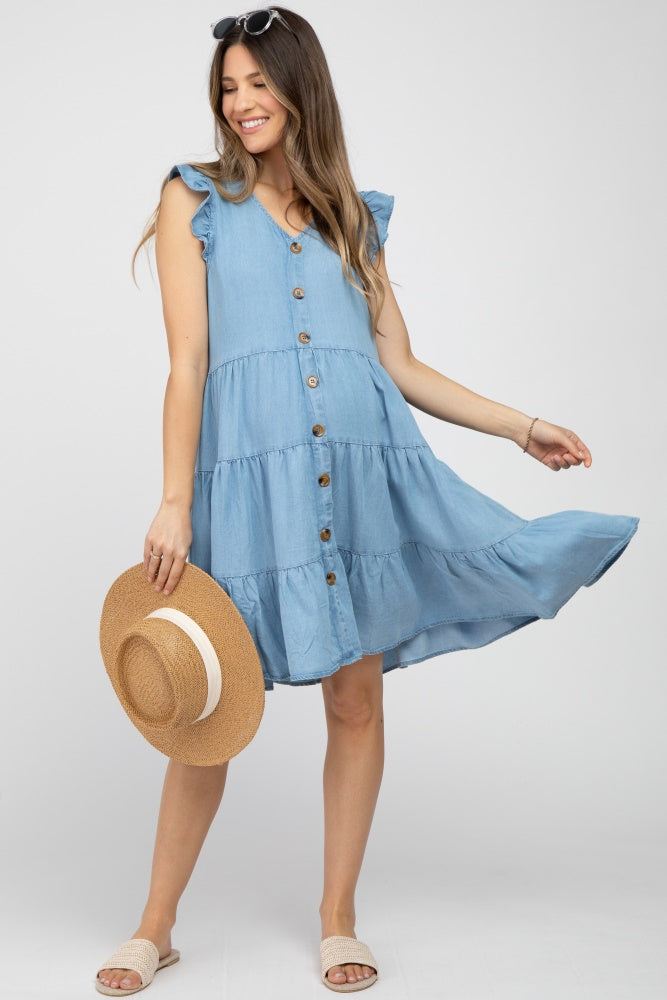 woman wearing a light blue tiered maternity dress with ruffle sleeves and button details, holding a straw hat and showing her baby bump