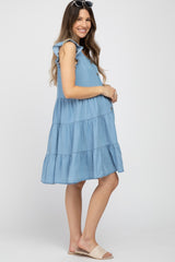 woman wearing a blue chambray maternity dress with ruffle sleeves and a tiered skirt, showing her baby bump