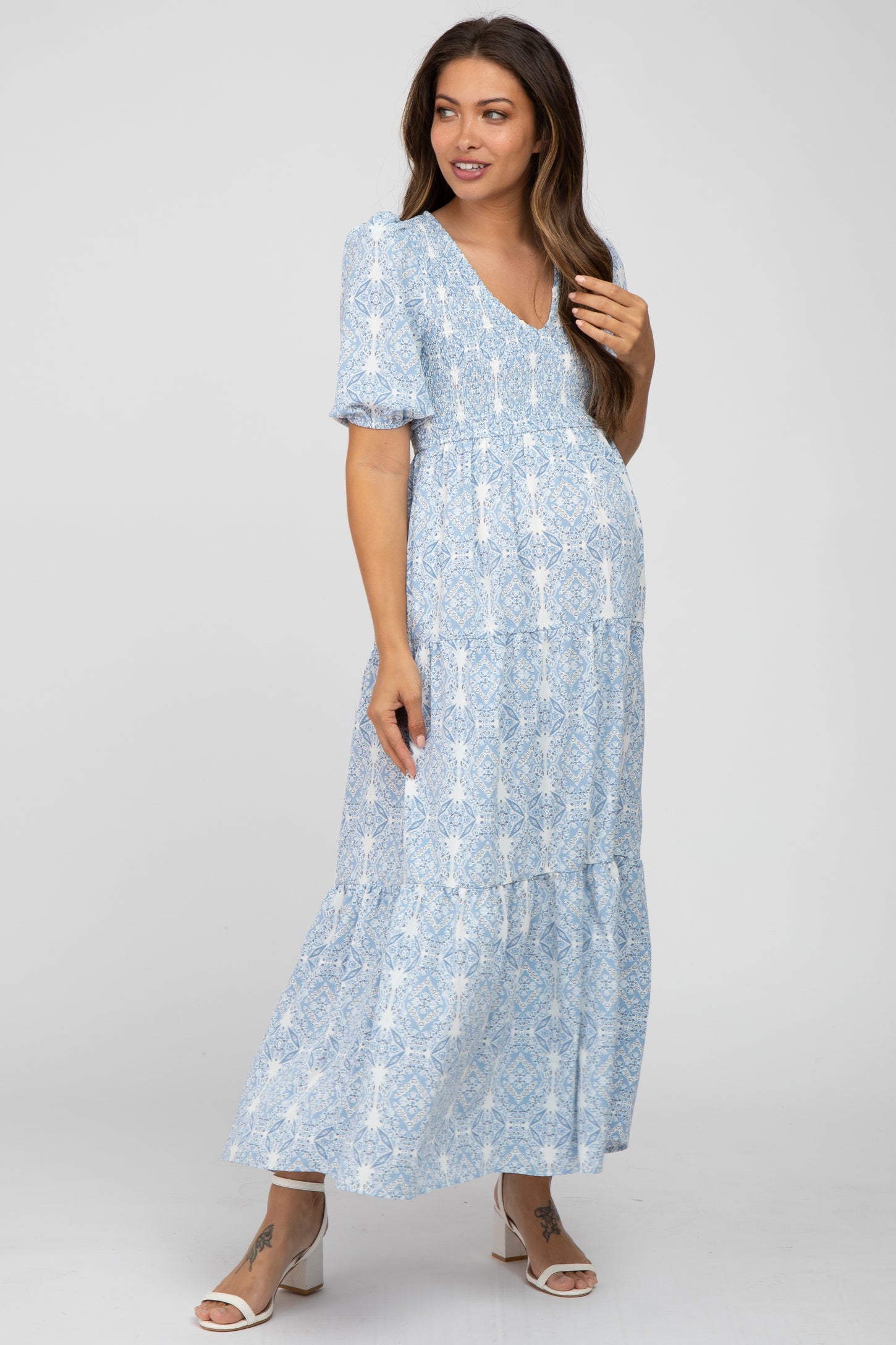 woman wearing a light blue maternity maxi dress with a v-neck and tiered hem, showing her baby bump