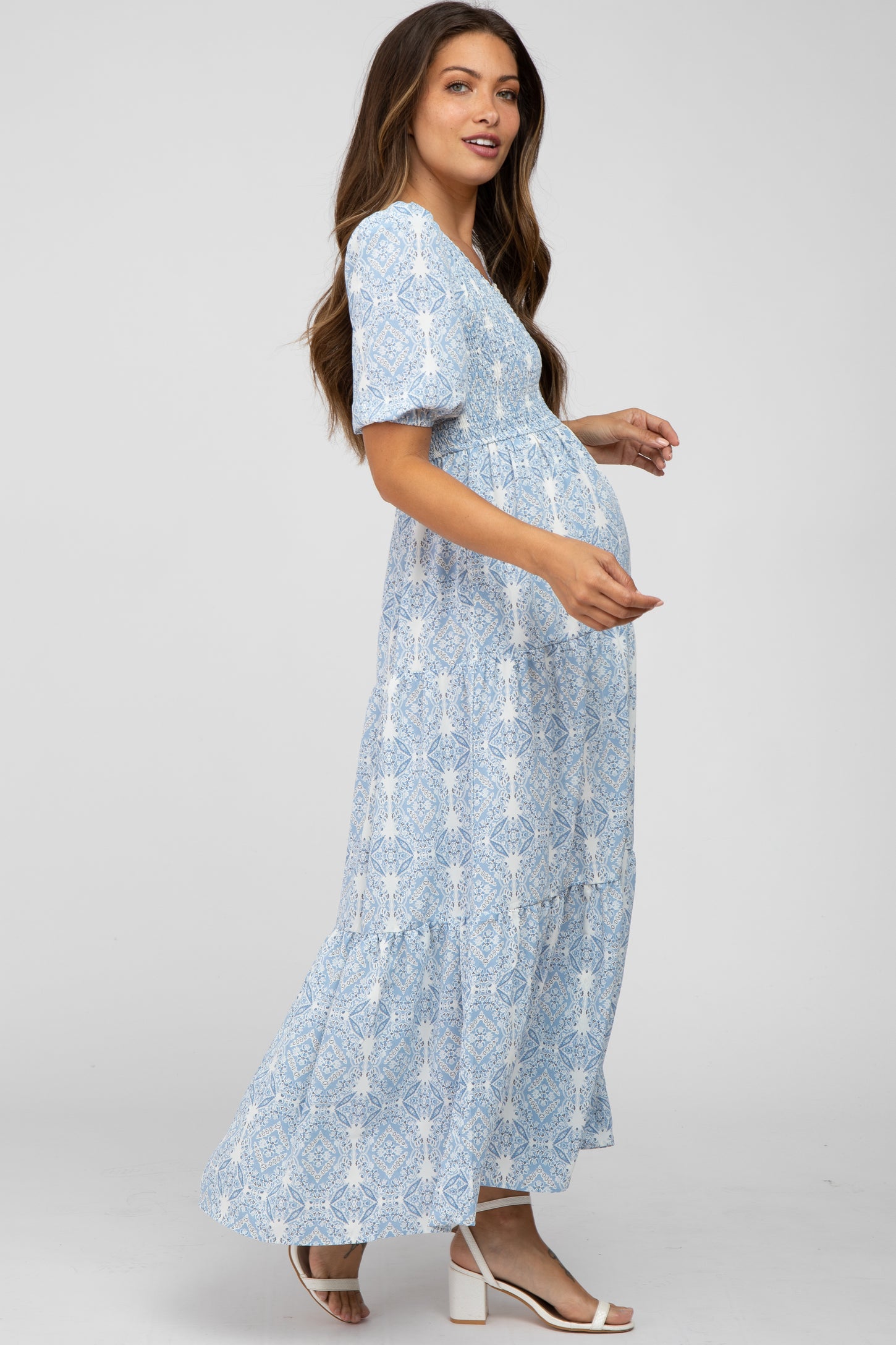 woman wearing a light blue patterned maternity maxi dress and holding her baby bump