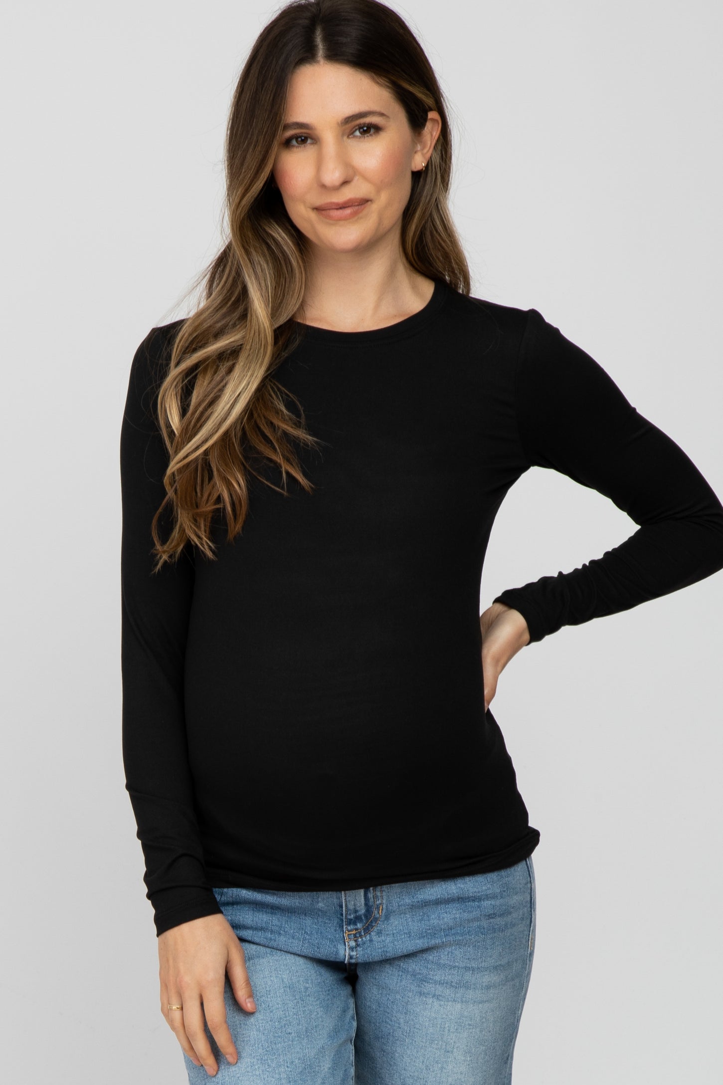 woman wearing a black long sleeve maternity top and showing her baby bump