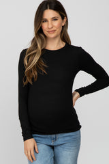 woman wearing a black long sleeve maternity top and showing her baby bump
