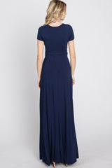 woman wearing a navy blue short sleeve maxi dress, showing the back view with a flowing skirt