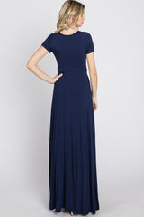 woman wearing a navy blue short sleeve maxi dress, showing the back view and a flowy skirt design