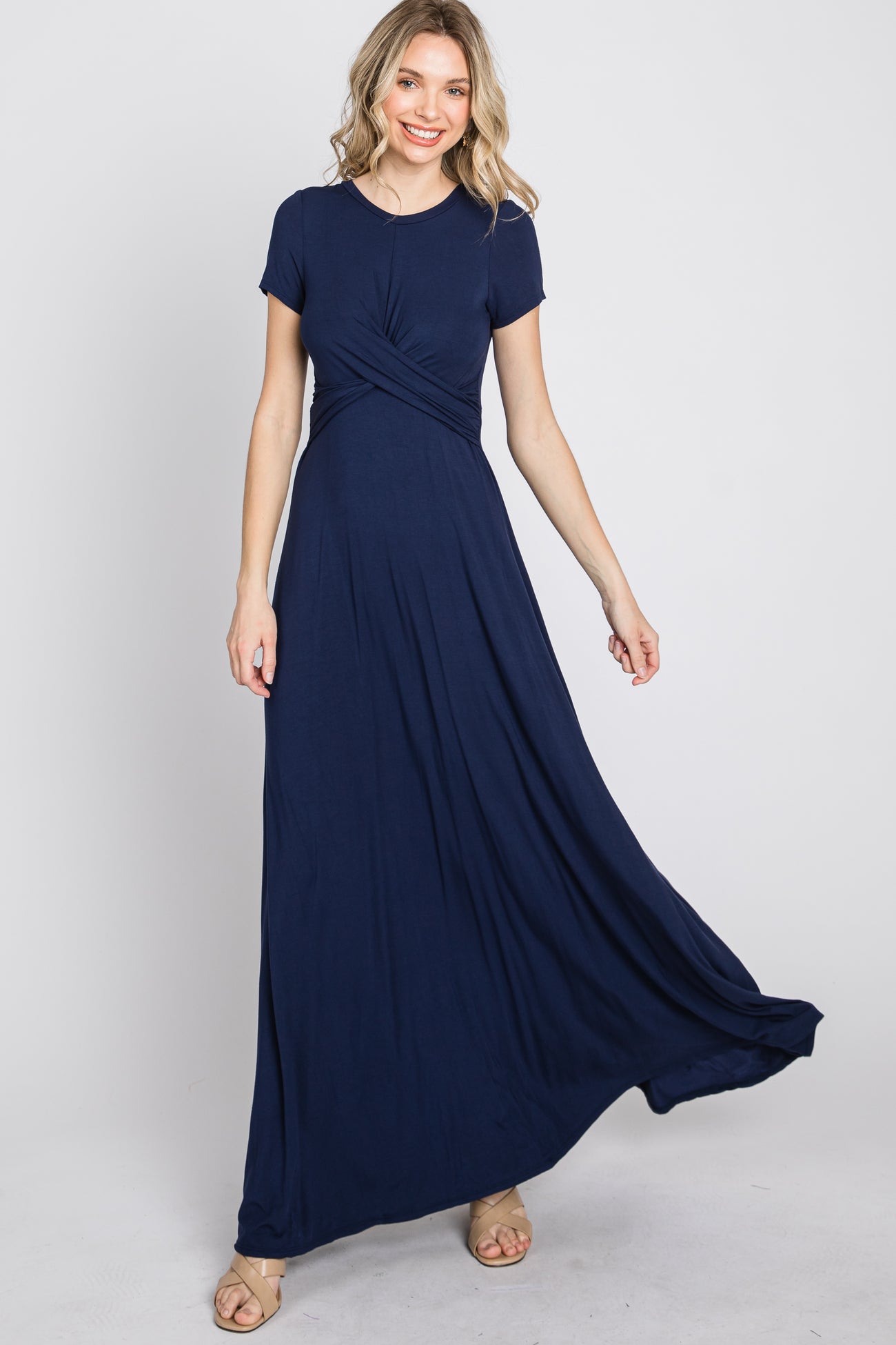 woman wearing a navy blue short sleeve maxi dress with a twisted bodice and flowing skirt