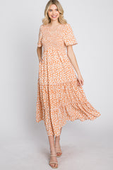 woman wearing a short sleeve orange floral maxi dress with a v-neck and tiered skirt, smiling at the camera