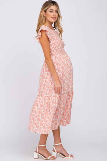 woman wearing a pink floral maternity dress with ruffle sleeves and a visible baby bump
