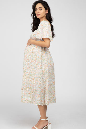 woman wearing a floral print maternity dress and holding her baby bump