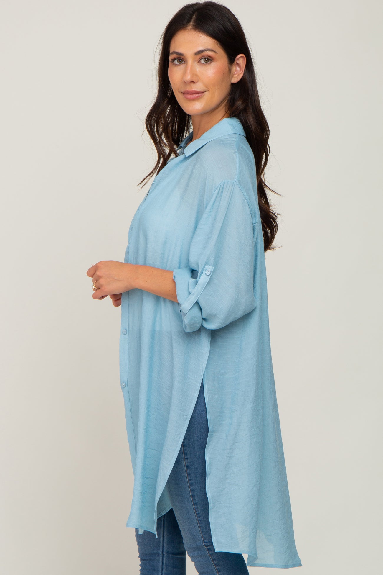 woman wearing a light blue long sleeve button-up shirt with rolled sleeves, paired with blue jeans