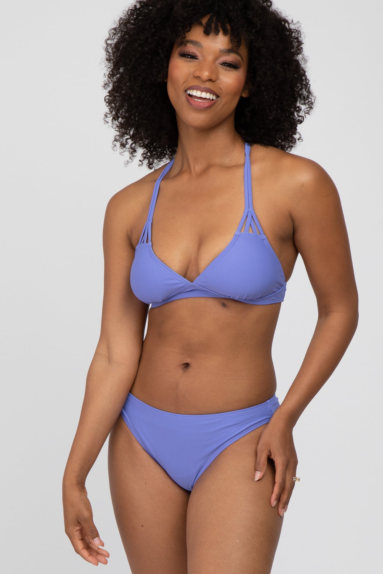 woman wearing a purple triangle bikini top with strappy details and matching bikini bottoms