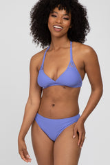 woman wearing a purple triangle bikini top with strappy details and matching bikini bottoms