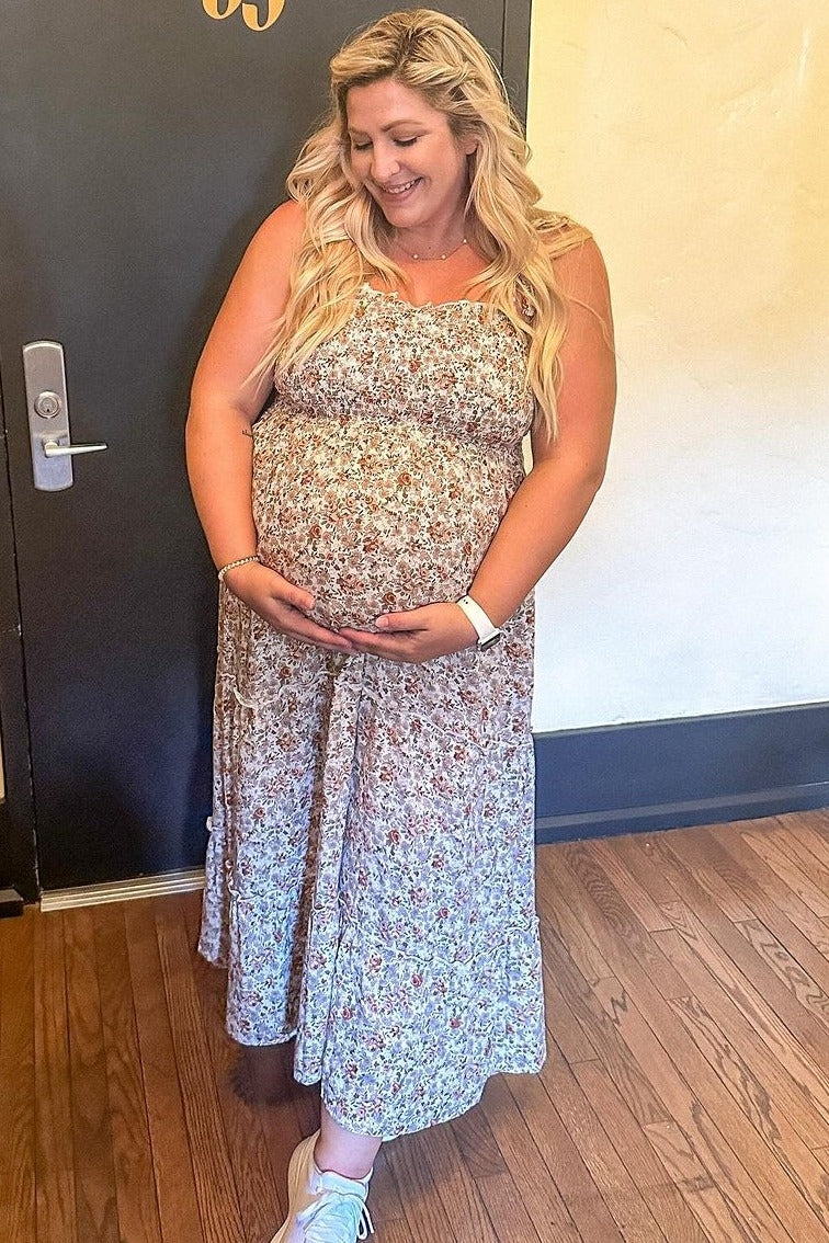 woman wearing a floral maternity maxi dress and holding her baby bump