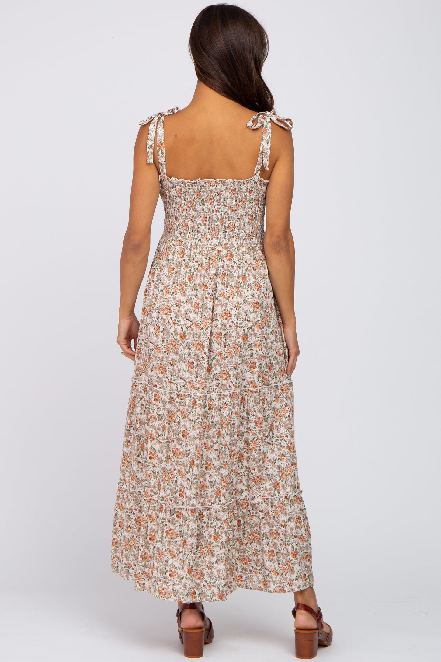 woman wearing a floral print maternity maxi dress with adjustable tie straps and a tiered skirt, showing a baby bump