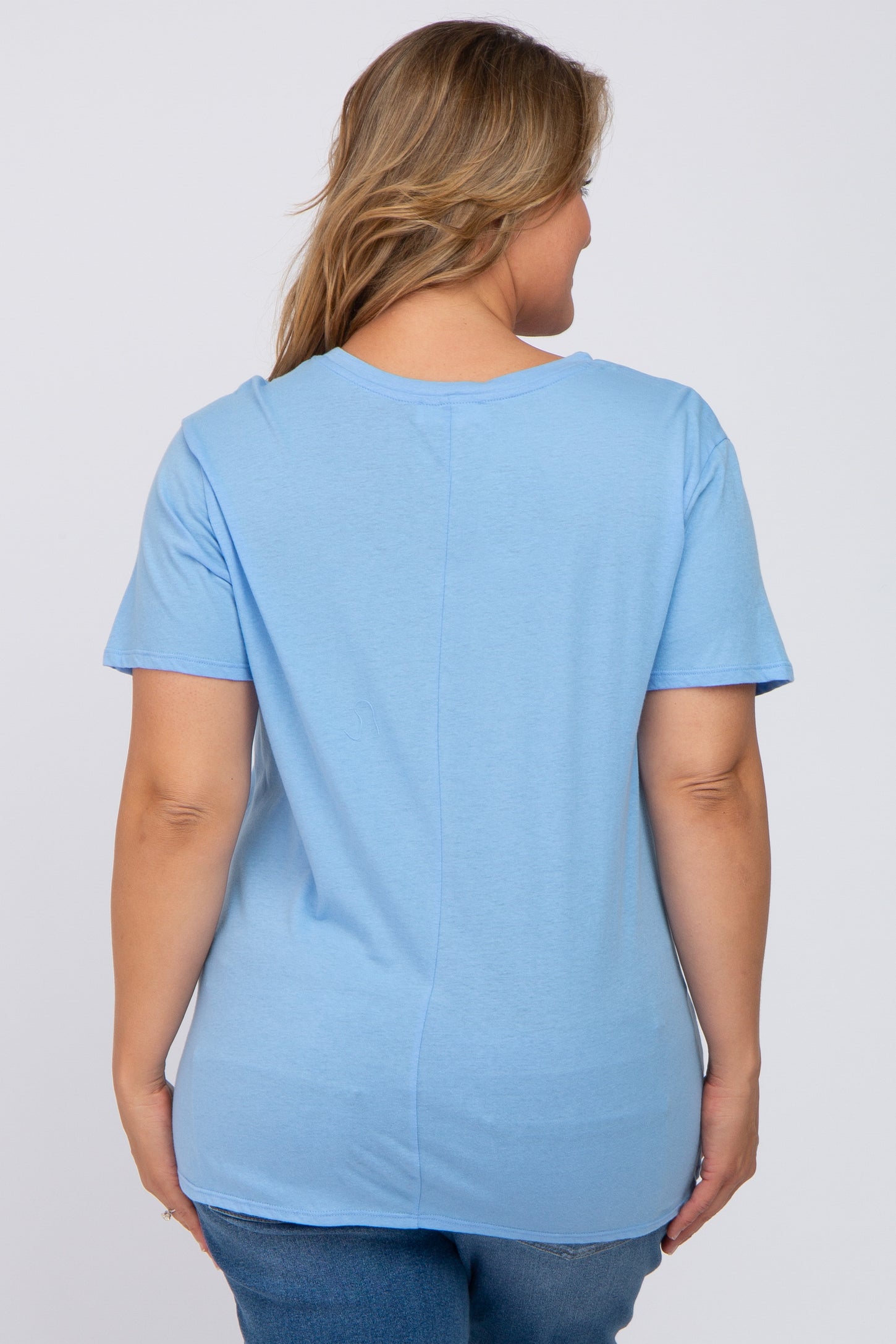 woman wearing a light blue short sleeve maternity top, viewed from the back, paired with blue jeans