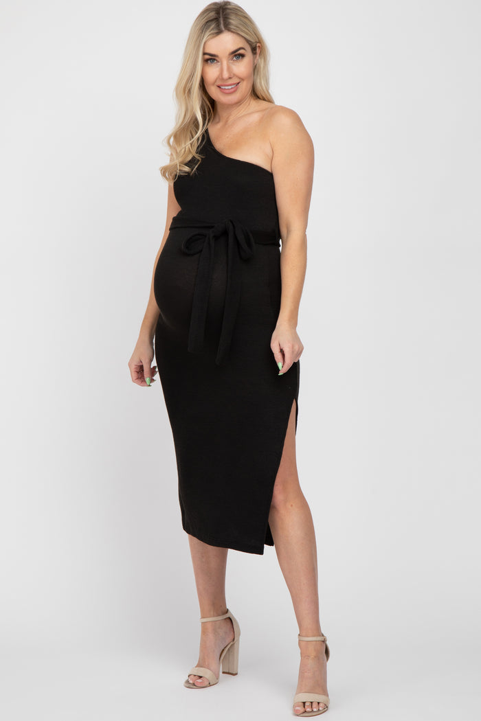 woman wearing a black one-shoulder maternity dress with a tie waist and side slit, showing her baby bump