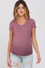 woman wearing a dusty mauve short sleeve maternity top with ruching and a visible baby bump, styled with distressed jeans
