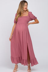 woman wearing a dusty rose maternity maxi dress with puff sleeves and a side slit, showcasing her baby bump