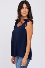 woman wearing a navy sleeveless top with tie shoulder details and casual jeans