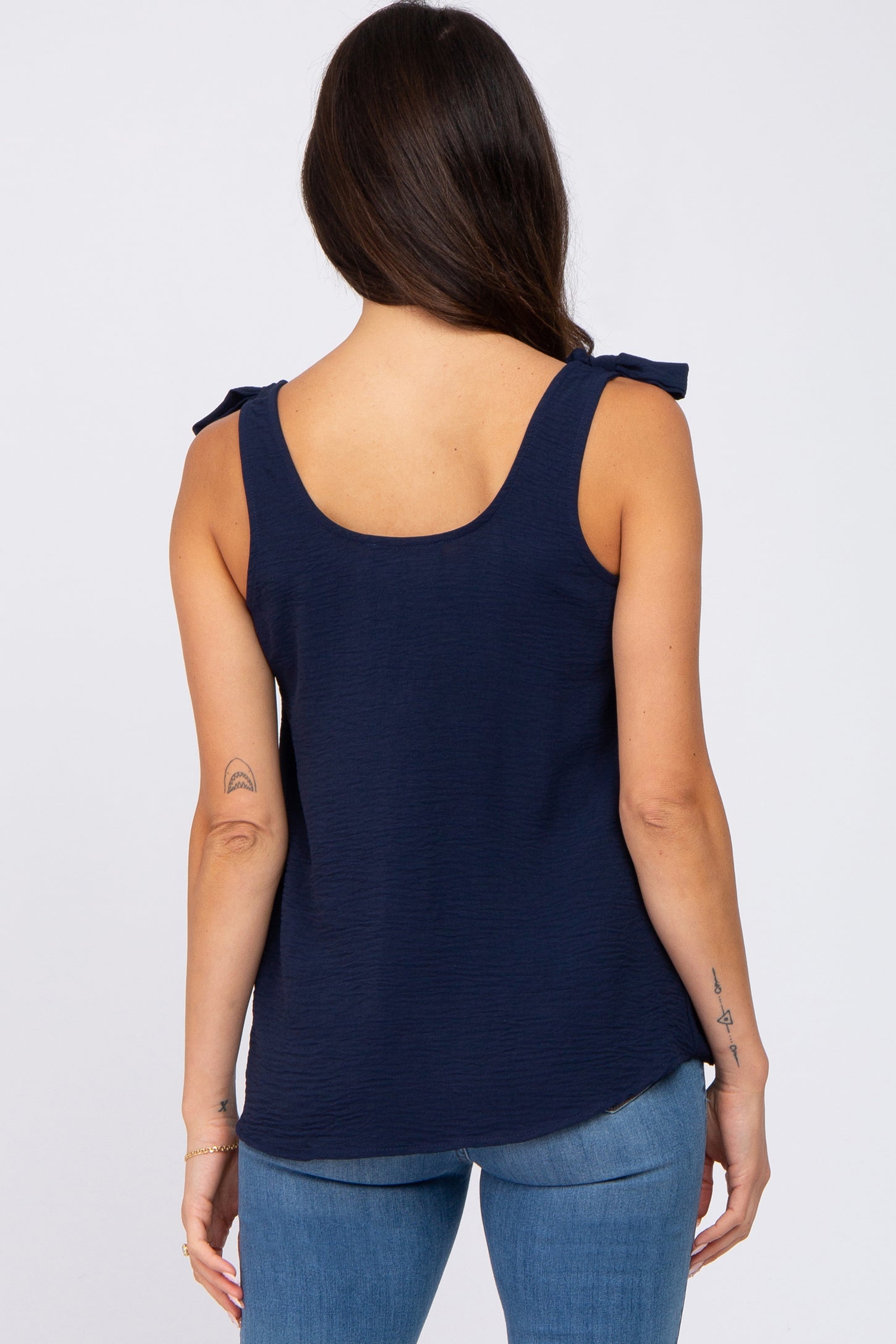 woman wearing a navy blue sleeveless top with bow shoulder details and back view shown