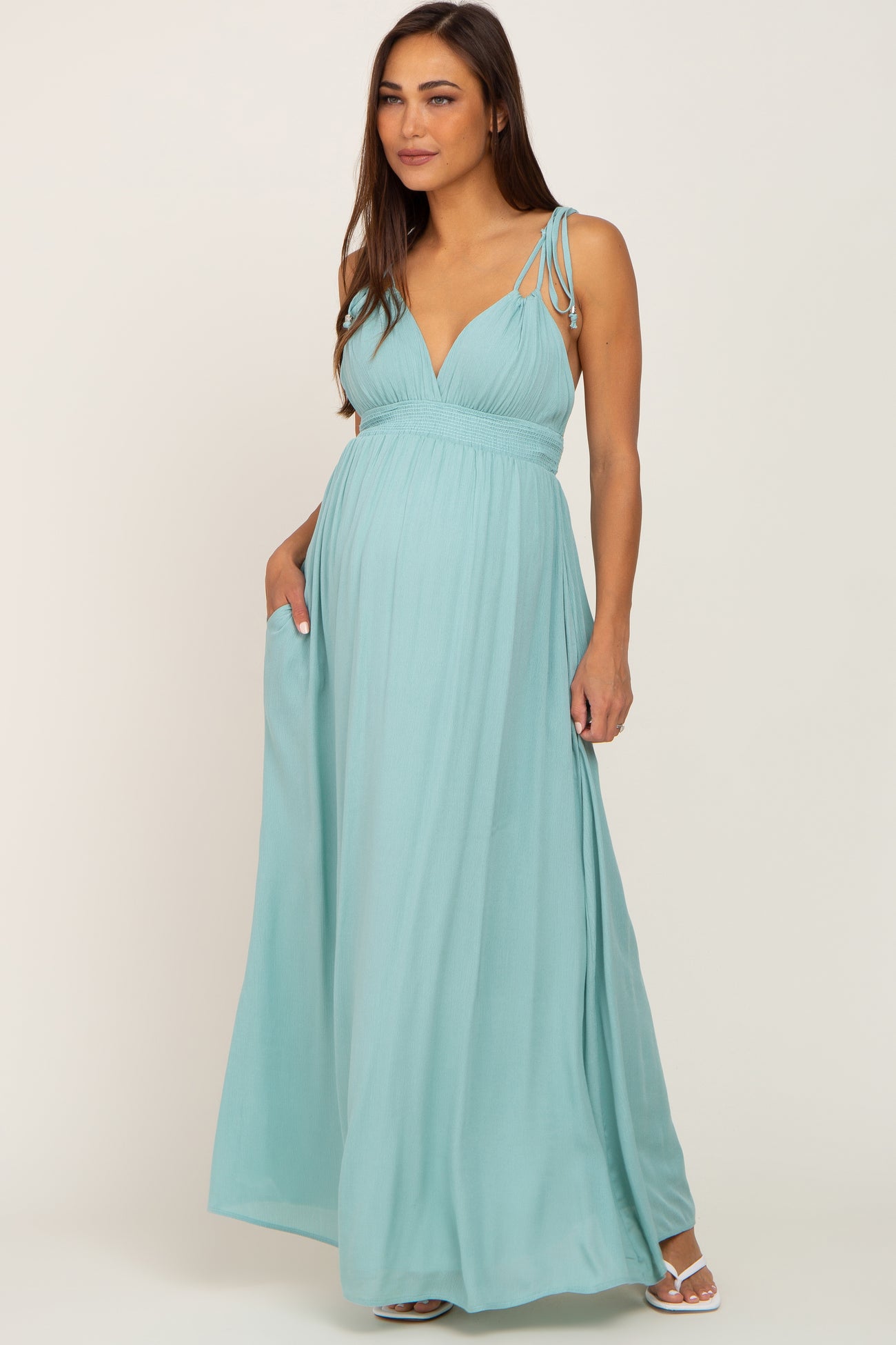 woman wearing a light blue maternity maxi dress with spaghetti straps and a flowing design, showing her baby bump