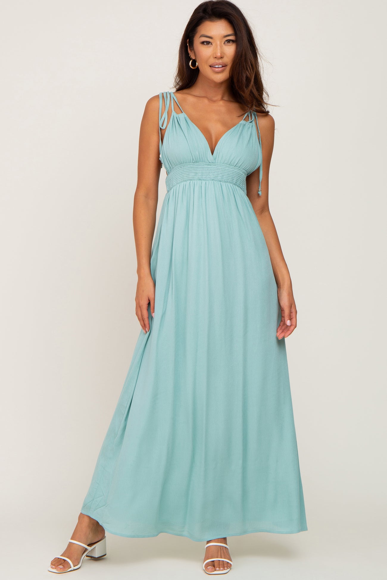 woman wearing a light teal maxi dress with adjustable straps and a fitted bodice