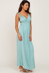 woman wearing a light teal maxi dress with tie shoulder straps and a fitted waist