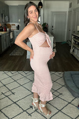 woman wearing a light pink maternity dress with a tie front and ruffle hem, showcasing her baby bump