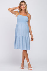 woman wearing a light blue maternity midi dress with smocked bodice and tiered skirt, showing baby bump