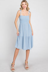 woman wearing a light blue tiered summer dress with adjustable tie straps and a smocked bodice