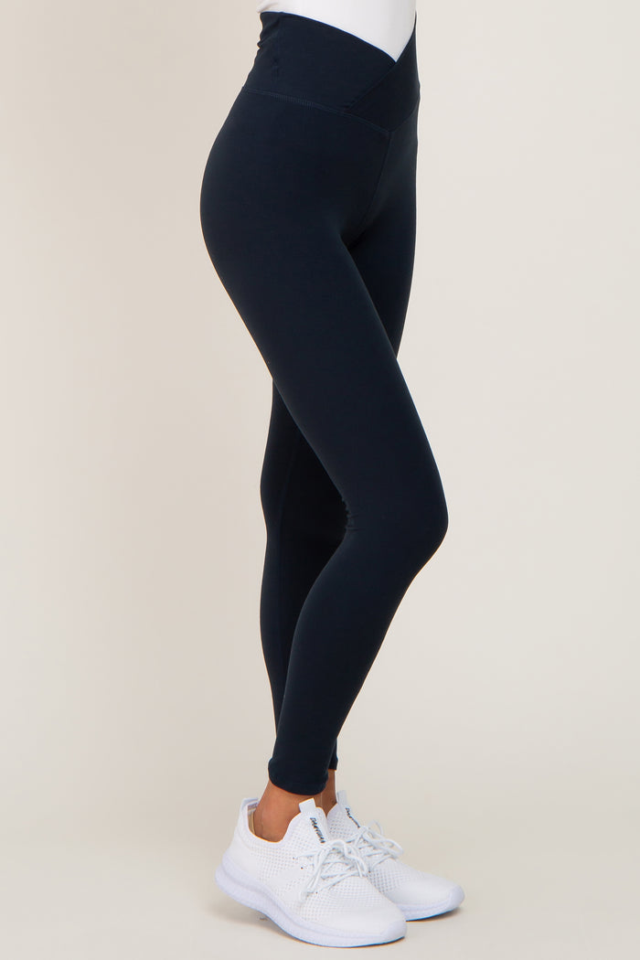 woman wearing high-waisted navy leggings and white athletic shoes
