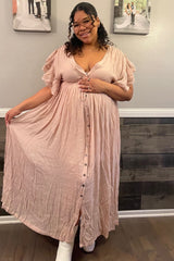 woman wearing a pink maternity maxi dress with ruffle sleeves and buttons, holding her baby bump