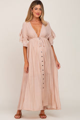 woman wearing a blush pink maternity maxi dress with a plunging neckline and buttons, showcasing her baby bump