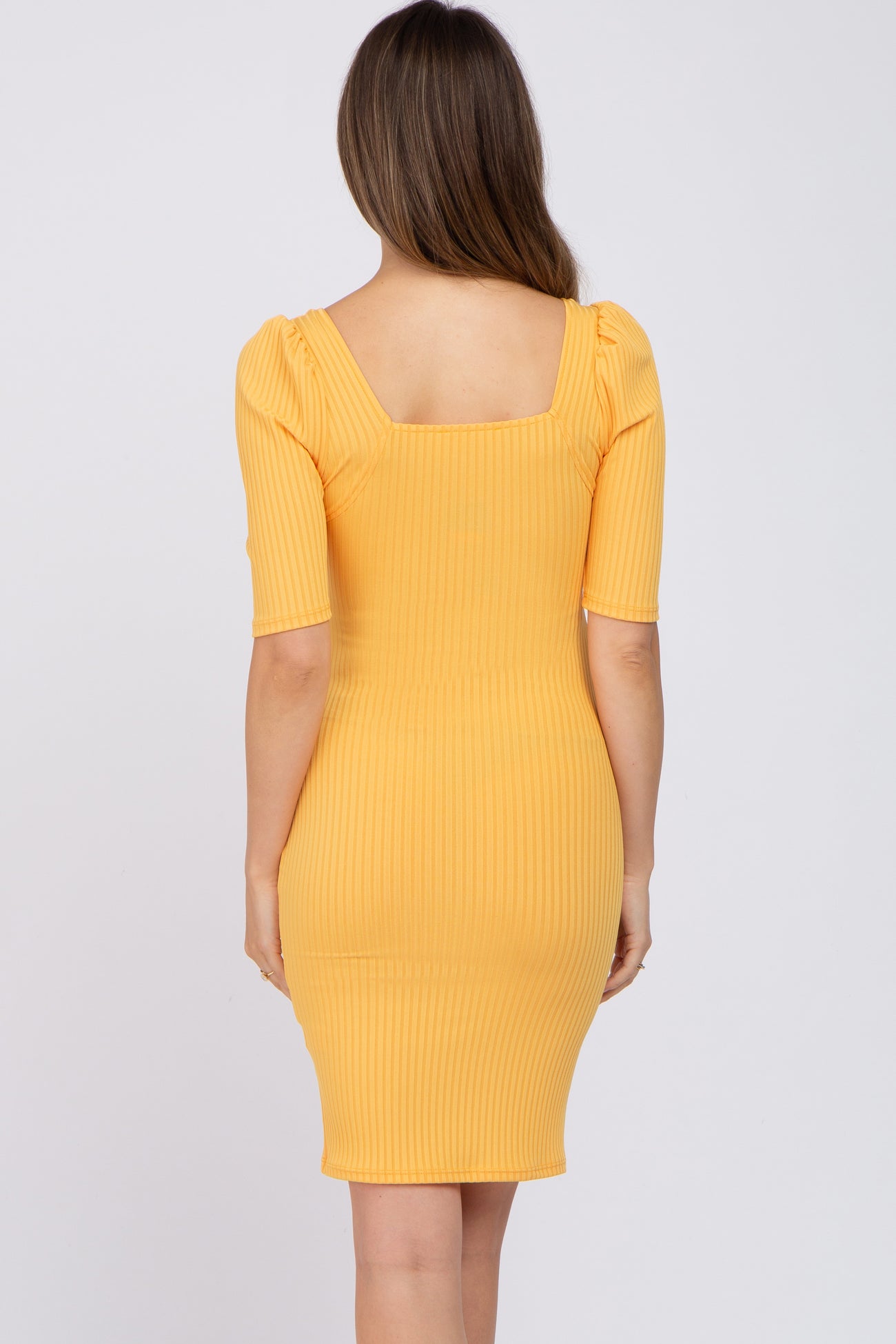 woman wearing a yellow ribbed maternity dress with short puff sleeves and a fitted silhouette