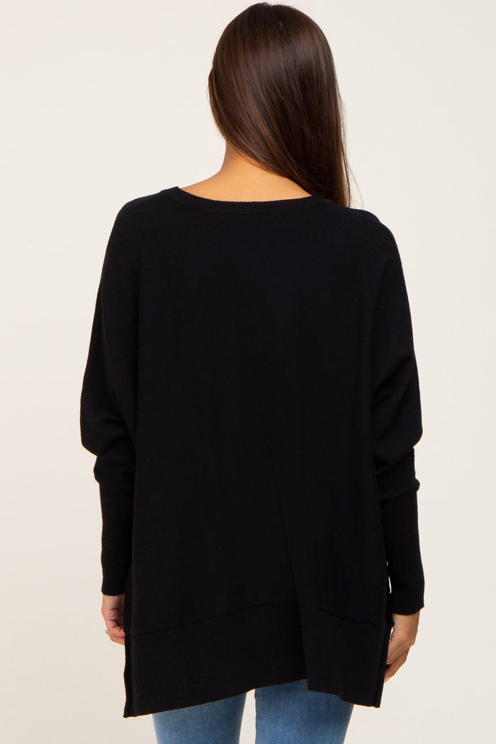 back view of a woman wearing an oversized black long sleeve sweater with blue jeans