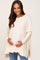 woman wearing a cream maternity sweater with a ruffle hem and holding her baby bump