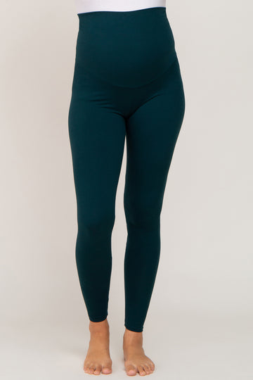 woman wearing green high-waisted maternity leggings with a support panel for a visible baby bump