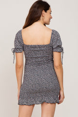 Back view of a woman wearing a navy blue daisy print mini dress with a square neckline and puff sleeves