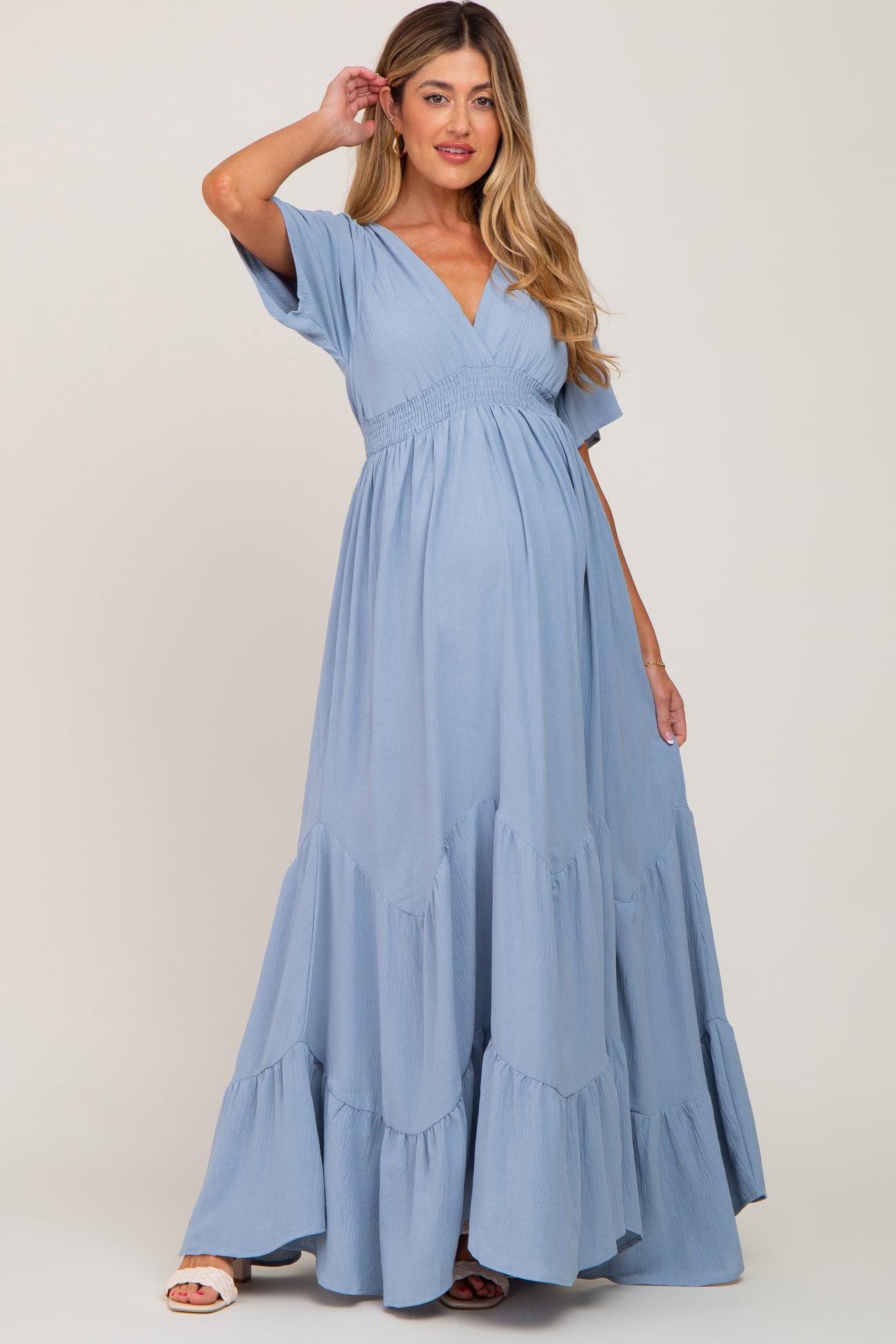 woman wearing a light blue tiered maternity dress with a v-neckline and short sleeves, showcasing her baby bump