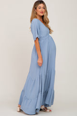 woman wearing a light blue maternity maxi dress with short sleeves and a tiered skirt, showing her baby bump