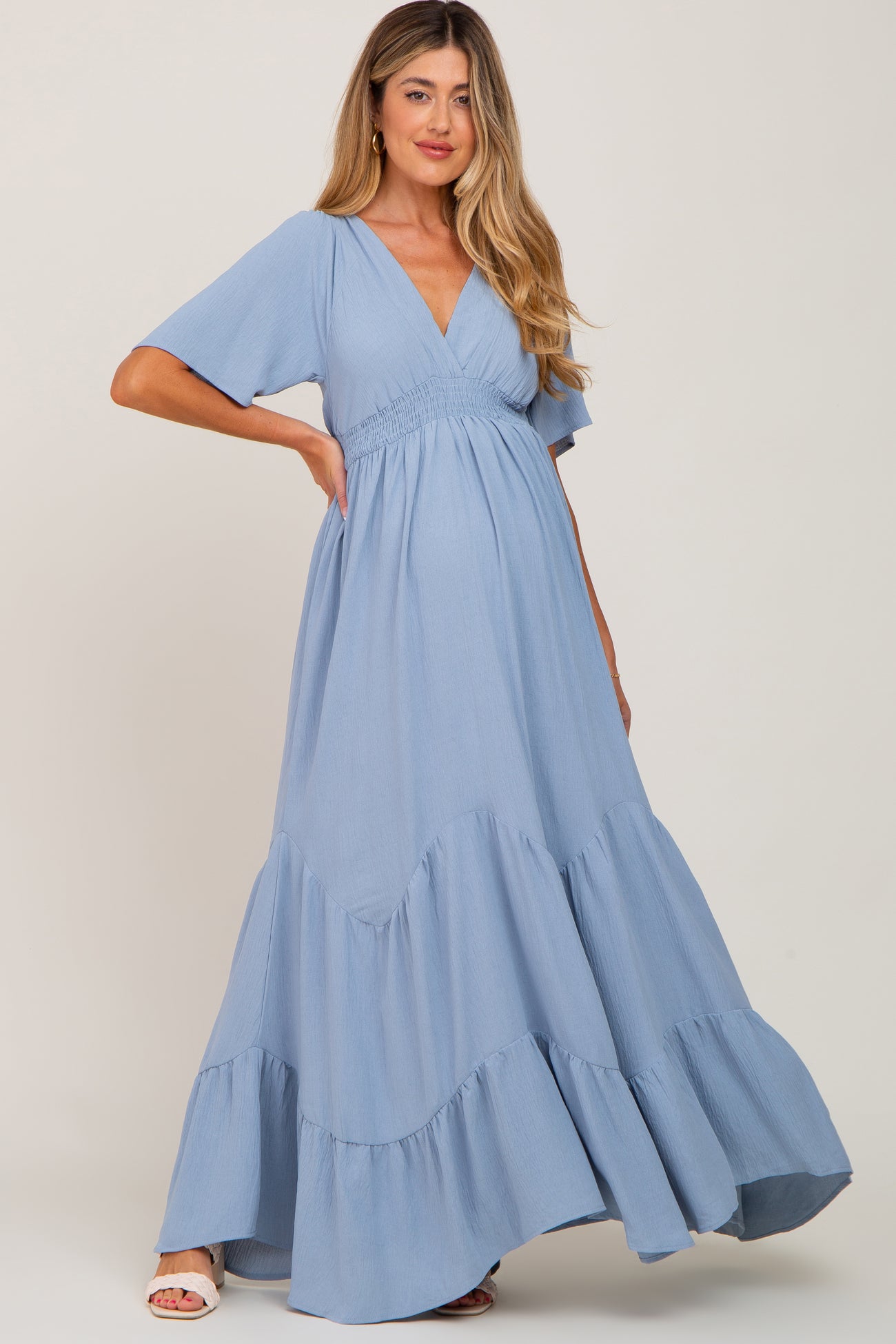 pregnant woman wearing a light blue short sleeve tiered maternity maxi dress with a v-neckline