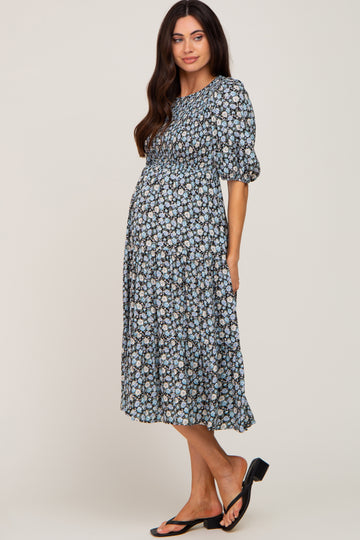 woman wearing a floral maternity dress with puff sleeves and a tiered skirt, showcasing her baby bump
