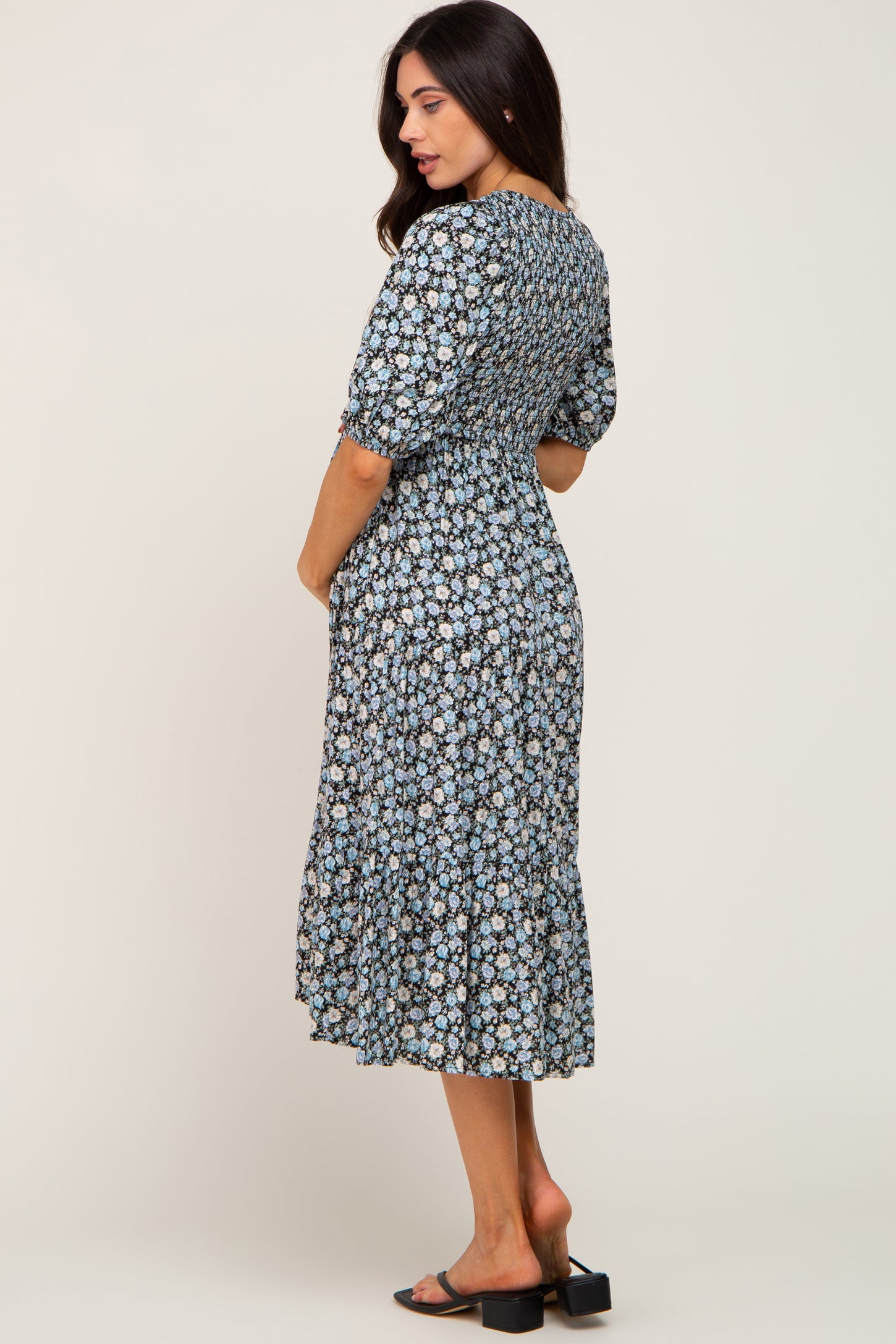 woman wearing a floral patterned maternity dress with a smocked bodice and ruffle hem, showcasing her baby bump